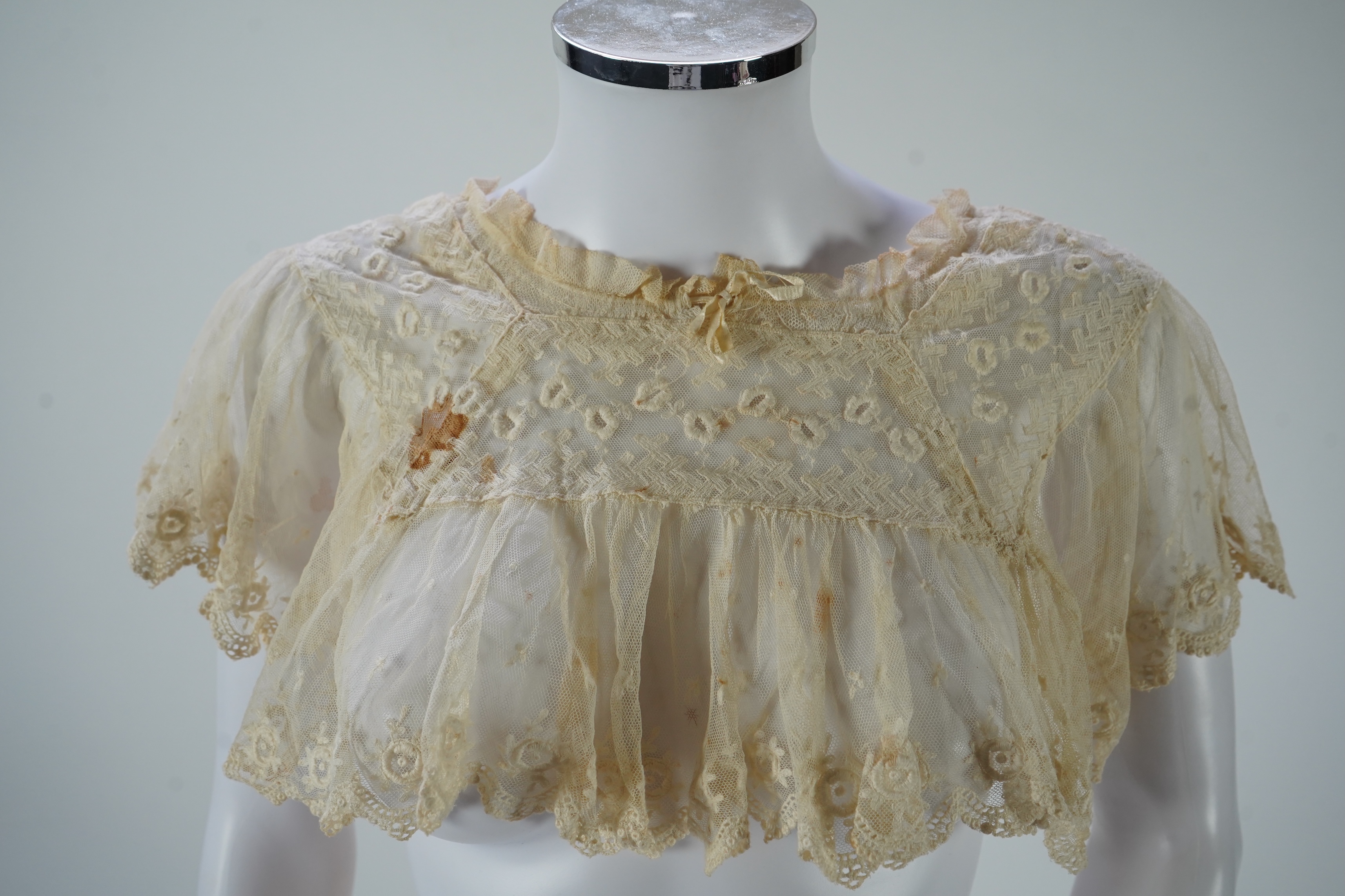 A suitcase containing a cream silk lace skirt to a dress, an Edwardian silk petticoat and various collars, possibly for theatrical use, silk petticoat 96 cm long. Condition - fair